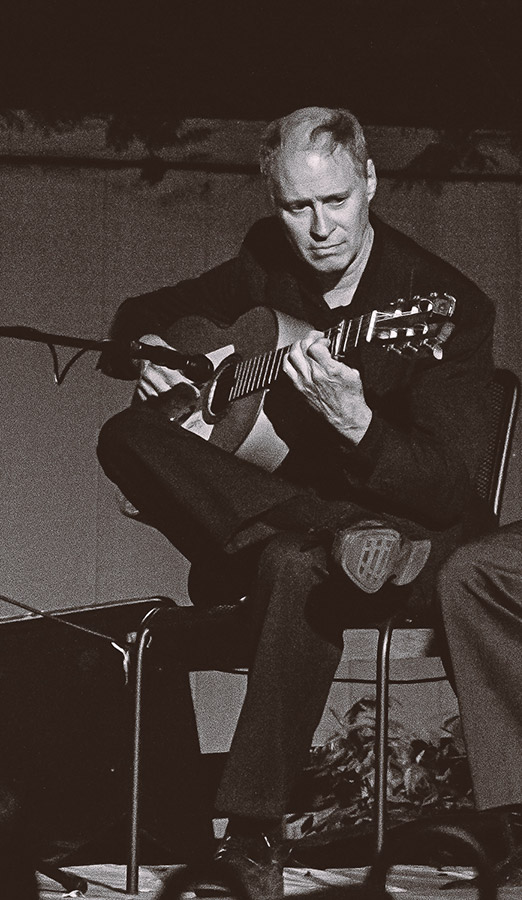 A photo of Johnny Beard playing the guitar on stage.